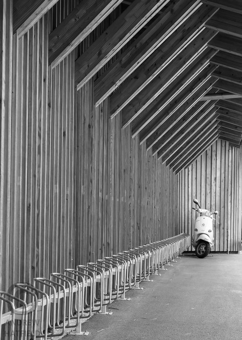 Black+and+white+image+showing+abstract+of+cycle+parking+area+with+laminated+timber+walls+and+roof+background+shows+parked+scooter+by+Andrew+Hatfield+P1090697.jpg